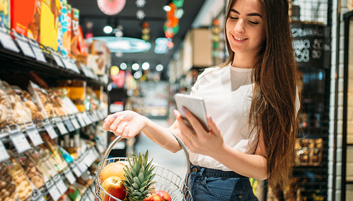 Eine junge Frau nimmt im Supermarkt an einem Konzepttest am Smartphone teil.