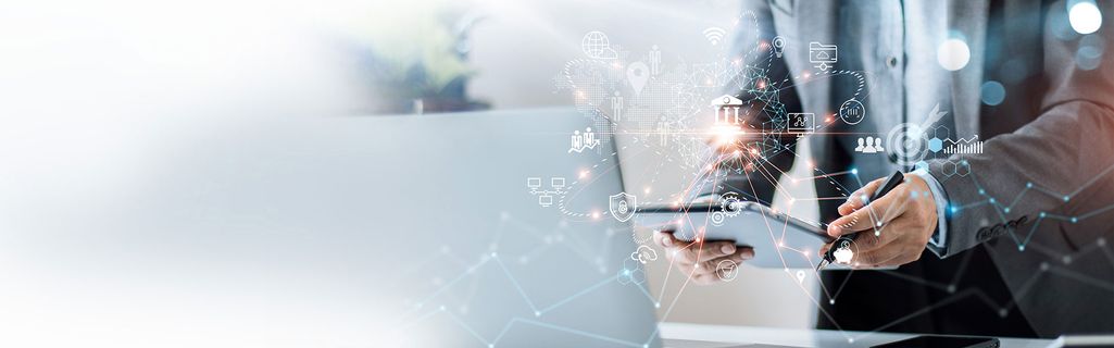 Eine Person steht mit einem Tablet vor dem Laptop und unternimmt eine Korrelationsanalyse.