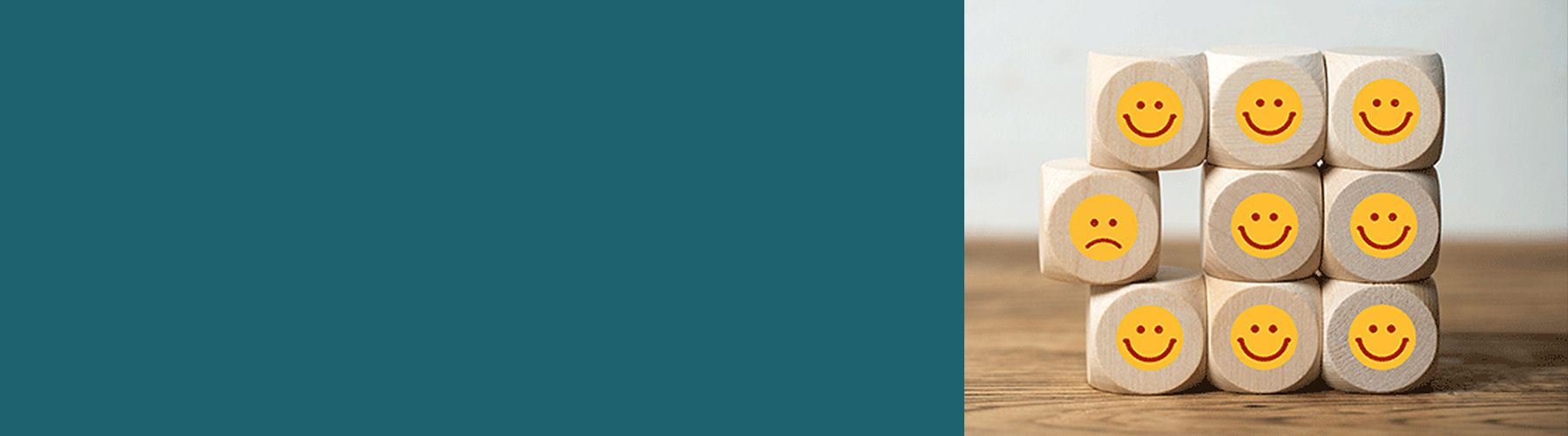 Mehrere Würfel sind übereinander gestapelt und haben Sticker mit teils lachenden und teils weinenden Smileys aufgeklebt. Diese symbolisieren die Kundenbefragung.