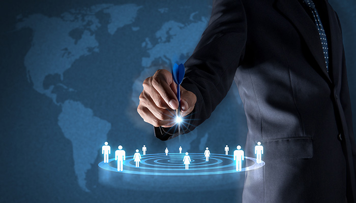 Mann zeigt mit Dartpfeil auf Zielscheibe mit Kundenicons: Durch eine Kundensegmentierung können einzelnen Kundengruppen noch individueller und gezielter angesprochen werden.