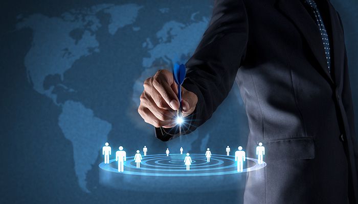 Mann zeigt mit Dartpfeil auf Zielscheibe mit Kundenicons: Durch eine Kundensegmentierung können einzelnen Kundengruppen noch individueller und gezielter angesprochen werden.