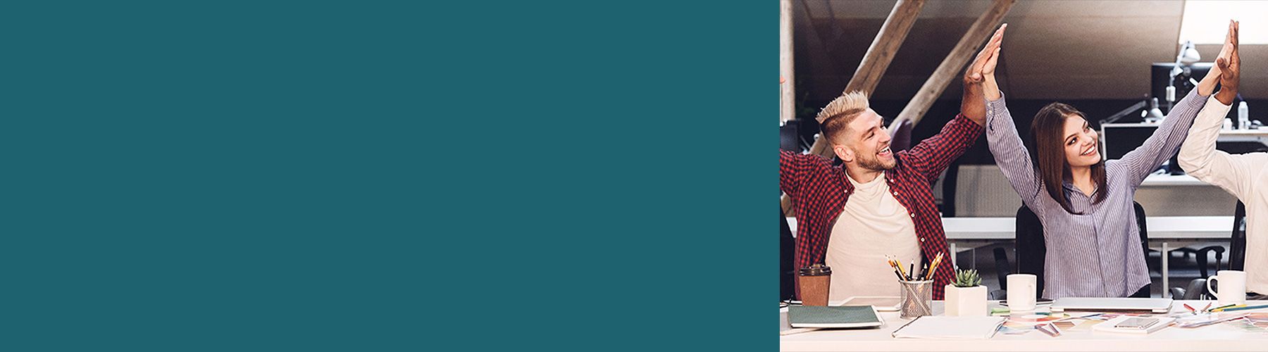 Ein junges Team sitzt lächelnd nebeneinander und symbolisiert durch gegenseitiges in die Hände klatschen eine gute Mitarbeiterbindung.