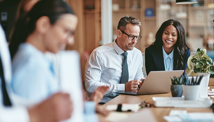 Eine erfahrene Mitarbeiterin zeigt dem neuen Mitarbeiter die unternehmenseigenen Prozesse als Teil des Onboardings.