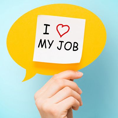 Eine Hand hält einen Notizzettel mit der Aufschrift Mitarbeiterzufriedenheit steigern in die Höhe.