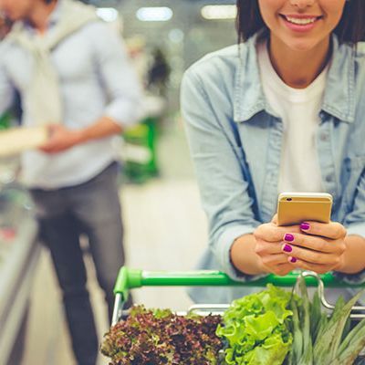 Mit dem NPSplus Kundenbegeisterung messen. Eine Frau steht mit einem vollem Einkaufswagen im Supermarkt.
