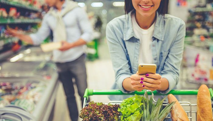 Mit dem NPSplus Kundenbegeisterung messen. Eine Frau steht mit einem vollem Einkaufswagen im Supermarkt.