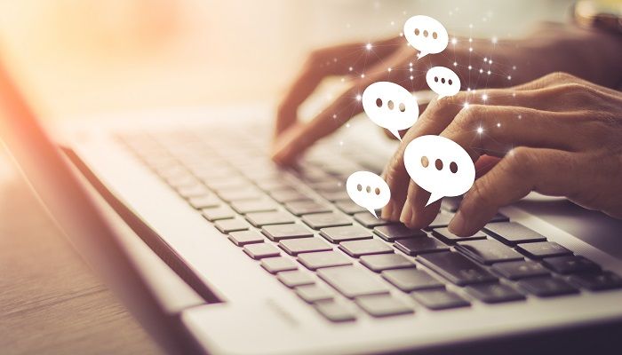 Es sind zwei Hände zu sehen die auf einem Laptop Tippen und Textanalyse Tools eingeben in das Suchfeld.