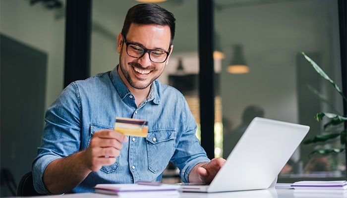 Mit dem Customer Effort Score den Kundenaufwand messen. Ein Man hält eine Kreditkarte in der Hand, während er online etwas bestellt.