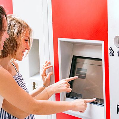 Zwei Frauen stehen vor einem Ticketautomaten und kaufen sich ein Deutschlandticket.
