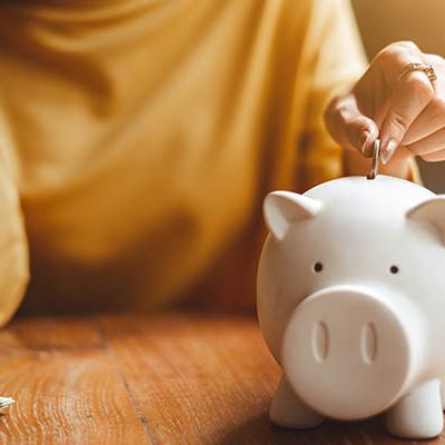 Jemand wirkt eine Münze in ein Sparschein als Symbol für die EZB Geldpolitik