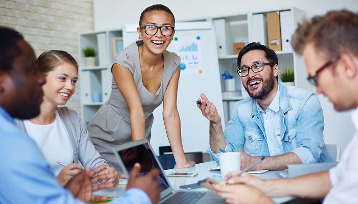 Mehrere Menschen sitzen an einem Meeting-Tisch und reden über den Employer Branding Index