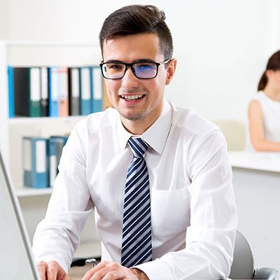 Ein Mann im Hemd sitzt vor dem PC und liest das Führungskräftefeedback durch.