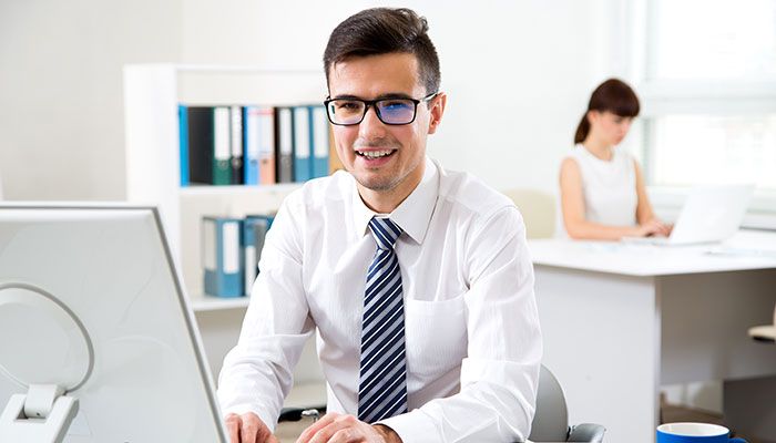 Ein Mann im Hemd sitzt vor dem PC und liest das Führungskräftefeedback durch.