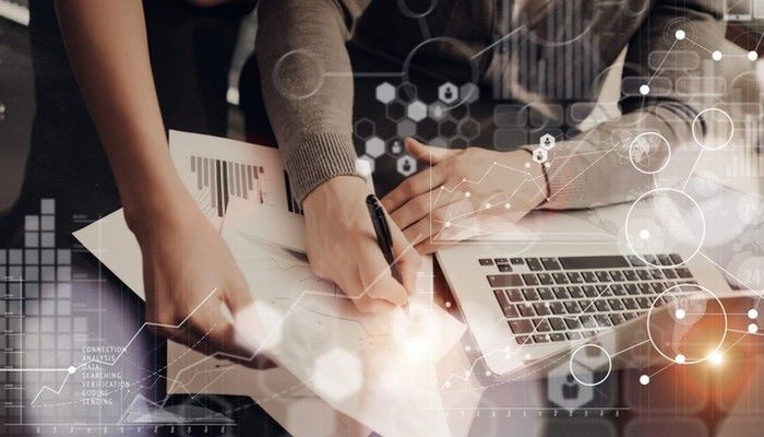 Zwei Personen planen am Schreibtisch mit Datenblättern und am Laptop einen Konzepttest.