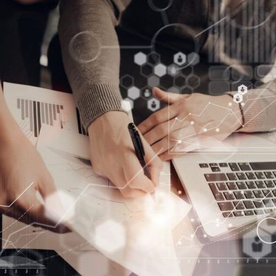 Zwei Personen planen am Schreibtisch mit Datenblättern und am Laptop einen Konzepttest.