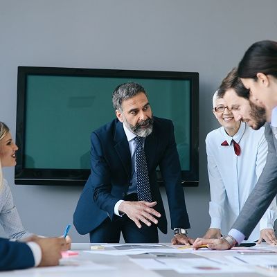 Mehrere Business Menschen sind in einem Raum und sprechen über den Mehrwert Führungskräftefeedbacks.