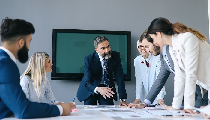 Mehrere Business Menschen sind in einem Raum und sprechen über den Mehrwert Führungskräftefeedbacks.