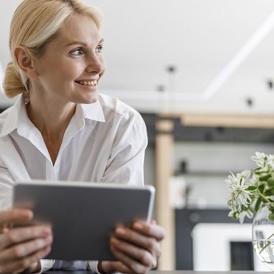 Eine Frau hat ein Tablet in der Hand und überlegt überlegt wegen Panel-Rekrutierung nach.