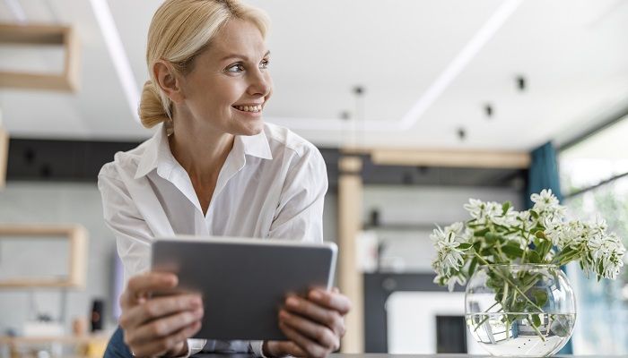 Eine Frau hat ein Tablet in der Hand und überlegt überlegt wegen Panel-Rekrutierung nach.