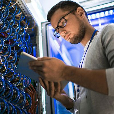 Ein Mann steht in einem Serverraum und liest eine Broschüre zum Prozess Schnittstellenanbindung.