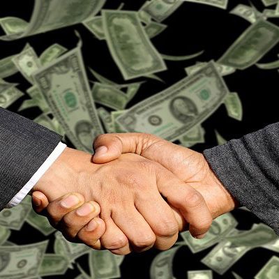 Handschlag mit Geld im Hintergrund
