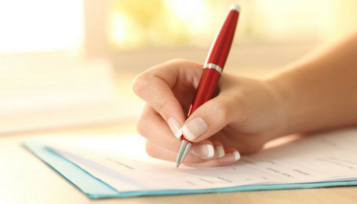 Eine Person füllt mir einem roten Kugelschreiber einen Fragebogen mit unterschiedlichen Fragetypen aus.