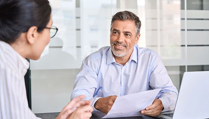 Ein Mann füllt mit einer Frau eine Mitarbeiterbefragung aus.