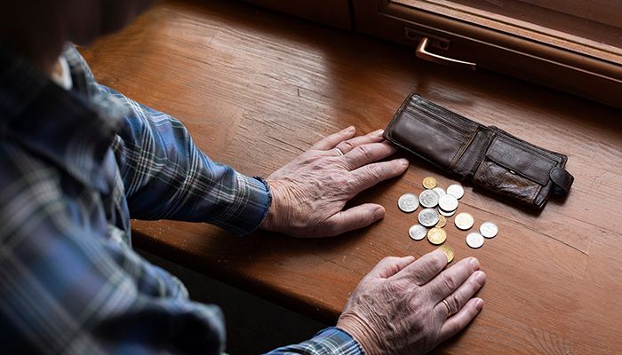 Man sieht zwei Hände und ein offener Geldbeutel mit wenigen Münzen.