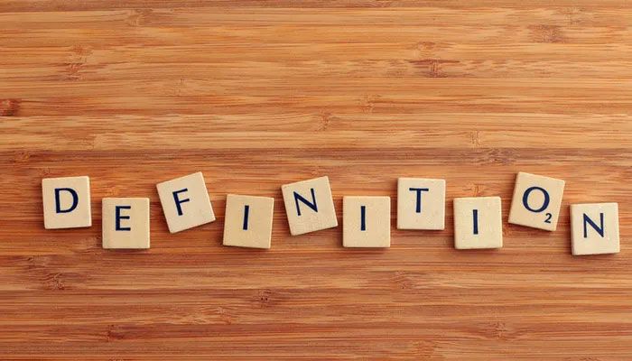 Es sind verschiedene Holzklötze mit Buchstaben auf einem Tisch verteilt, die zusammen die Wörter Definition der Kundenzufriedenheit ergeben.