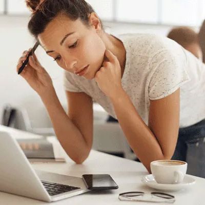 Eine Frau schaut angestrengt auf einen Laptop auf dem sie gerade einen Fragebogen ausfüllt.