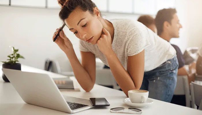 Eine Frau schaut angestrengt auf einen Laptop auf dem sie gerade einen Fragebogen ausfüllt.