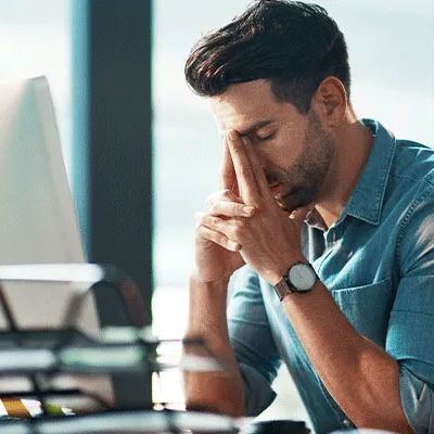 Was kann eine Gefährdungsbeurteilung online leisten und was kann sie nicht? - Mann sitzt erschöpft vor dem Bildschirm und stützt Kopf in die Hände.