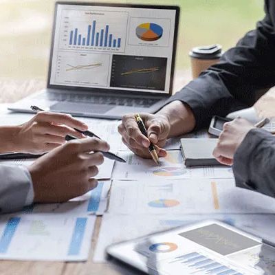 Konzepttests - Menschen im Büro zeigen auf mit Stiften auf verschiedene Graphen und Auswertungen.