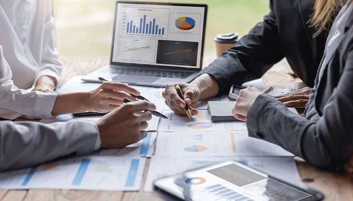 Konzepttests - Menschen im Büro zeigen auf mit Stiften auf verschiedene Graphen und Auswertungen.