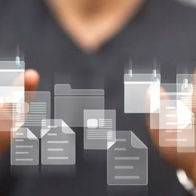 Zwei Hände halten viele Textdokumente die mit einer Textanalysesoftware bearbeitet werden müssen.