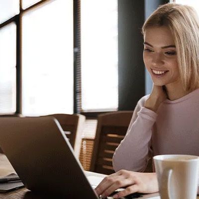 Junge Frau sitzt lächelnd vor ihrem nimmt mit Laptop. Offenbar ist sie zufrieden mit ihrer alternativen Incentivierung.