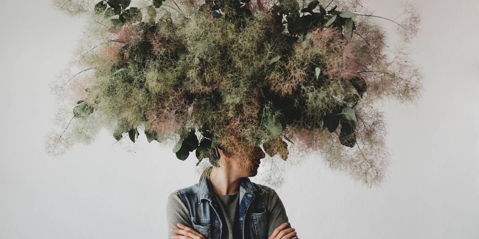 Large decorative bouquet made of green leaves and moss hangs over man's head
