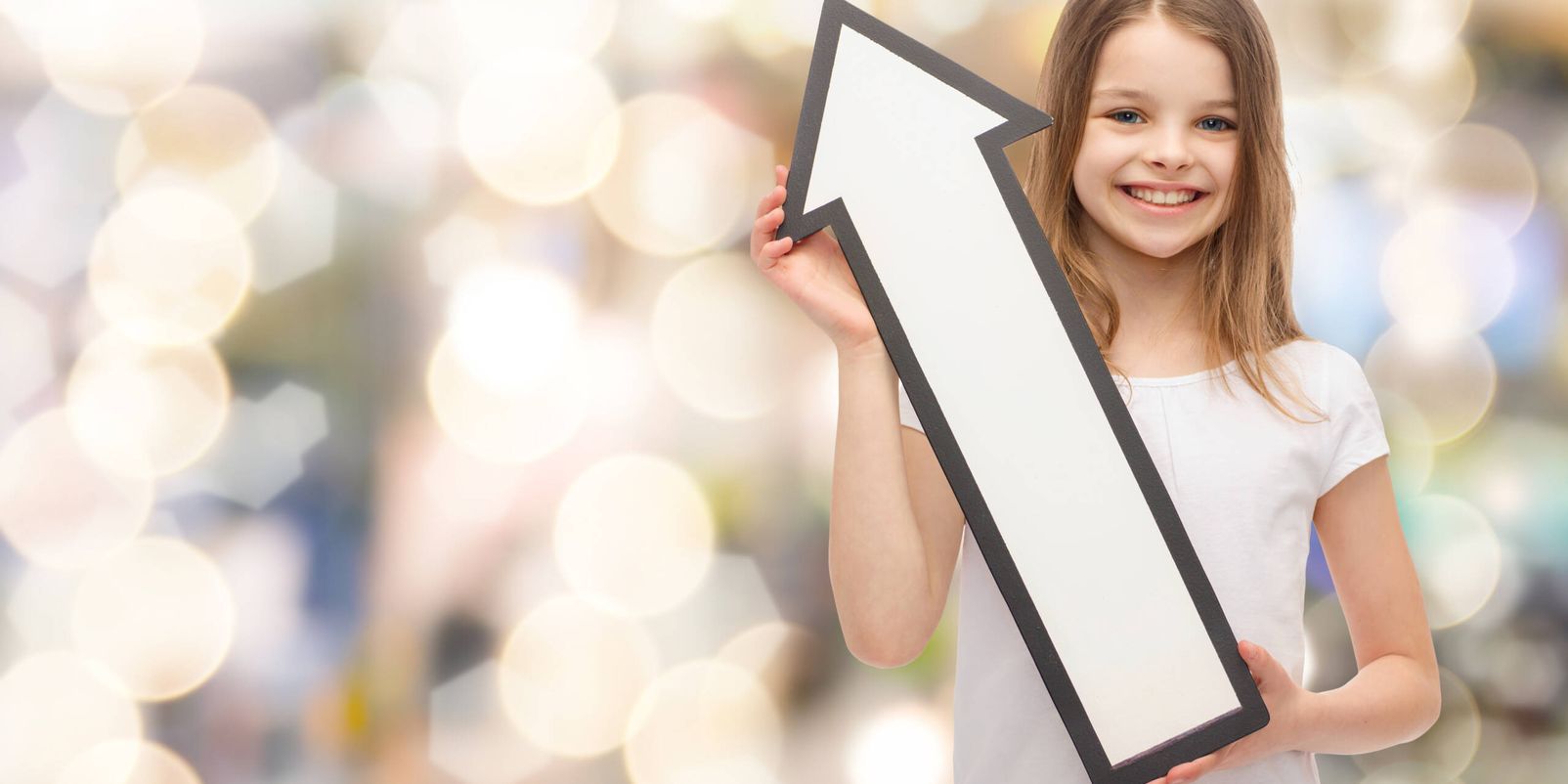 advertising and child concept - smiling little girl with blank arrow pointing up