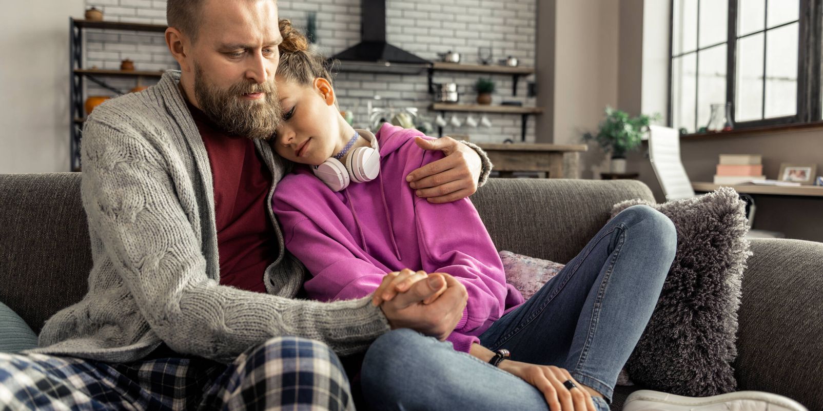 Leaning on shoulder. Teenage daughter wearing jeans and sneakers leaning on shoulder of supportive father