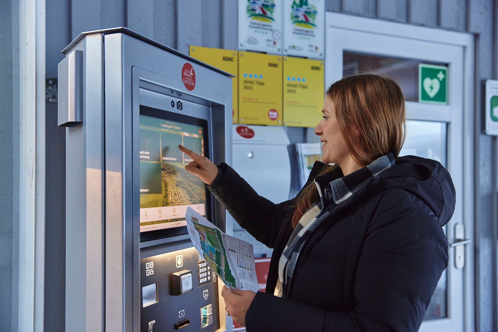 Frau nutzt den Checki-Automaten auf dem Campingplatz Rantum