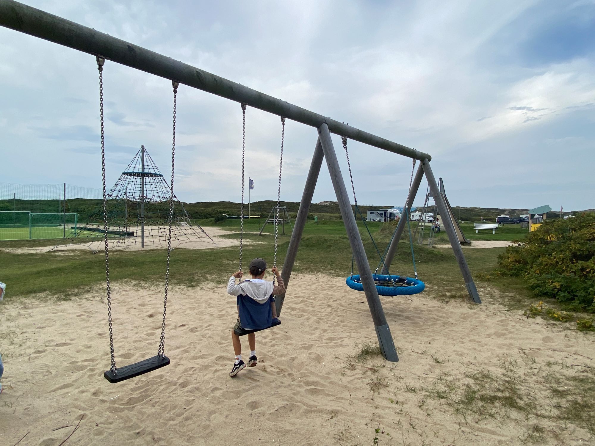 Junge schaukelt auf dem Spielplatz auf dem Campingplatz Rantum
