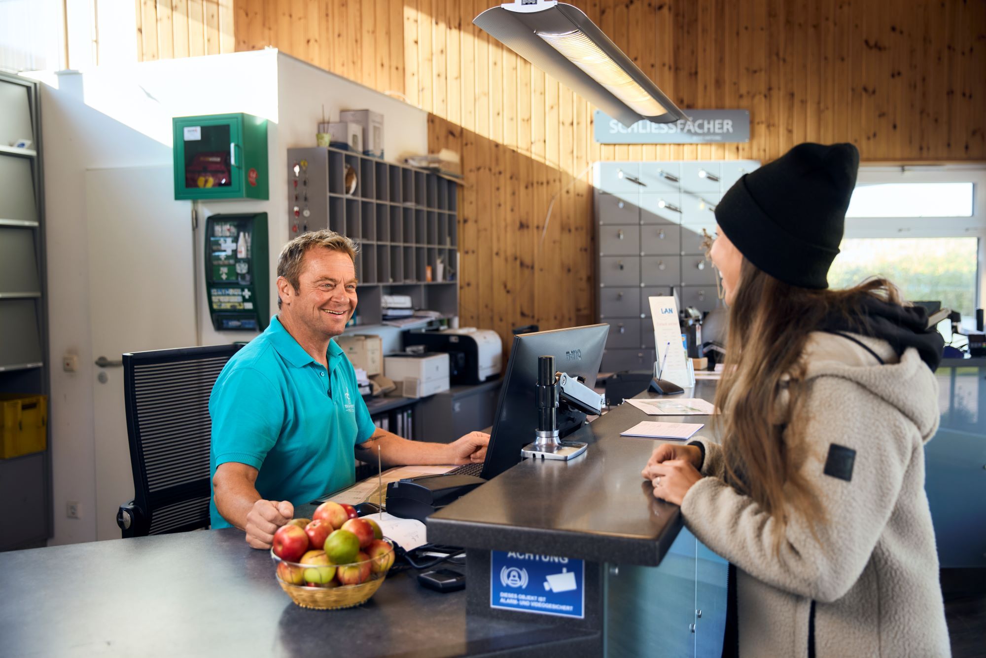 Weiblicher Gast lässt sich in der Rezeption des Campingplatzes Rantum von männlichem Mitarbeiter beraten