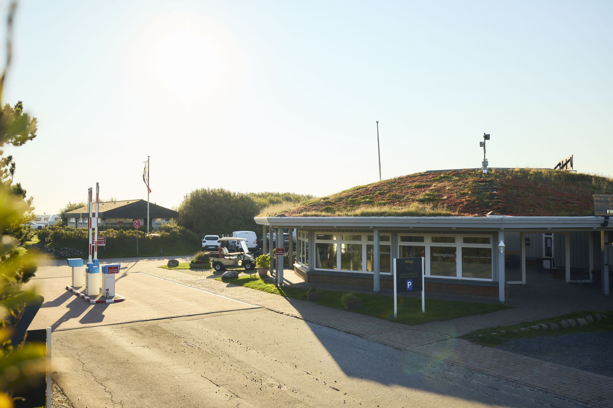 Außenansicht des Rezeptionsgebäudes mit der offenen Schranke zum Campingplatz Rantum