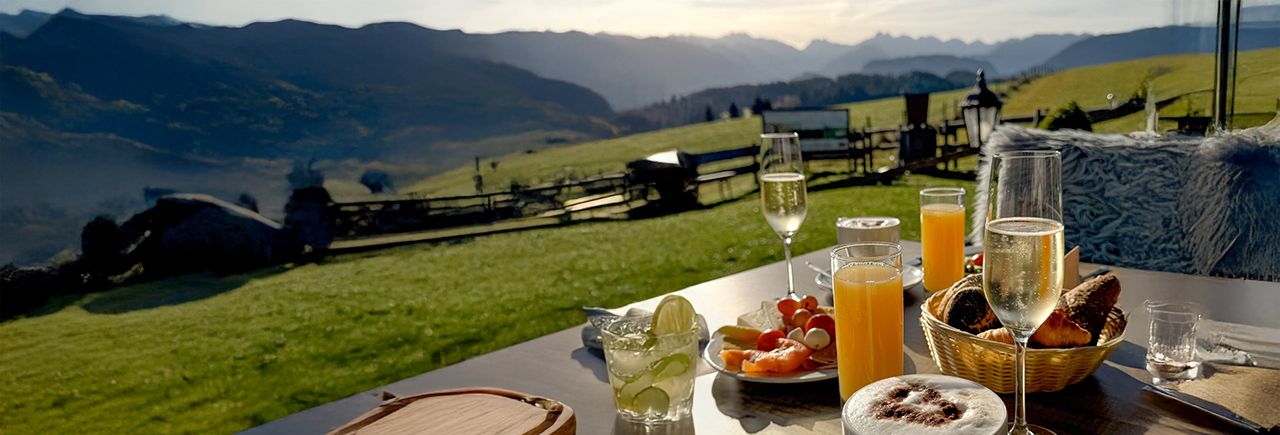 Frühstück auf Tisch. Im Hintergrund ein Ausblick auf die Berge.