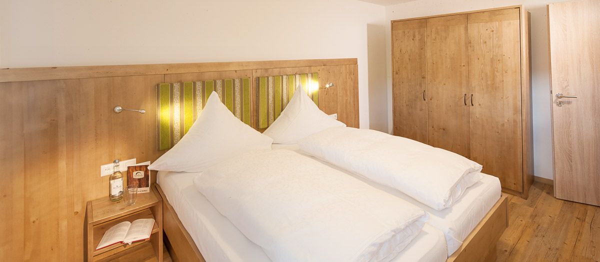 Gemütliches Doppelzimmer im Ferienhof Gaisbock in Fischen im Allgäu – stilvoll in Holzoptik eingerichtet, mit warmem Licht für entspannte Urlaubstage.