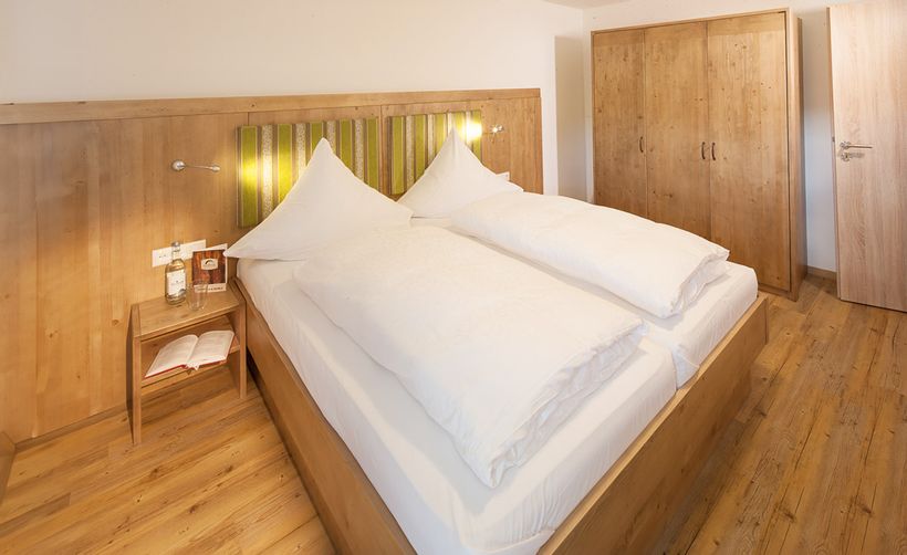 Gemütliches Doppelzimmer im Ferienhof Gaisbock in Fischen im Allgäu – stilvoll in Holzoptik eingerichtet, mit warmem Licht für entspannte Urlaubstage.