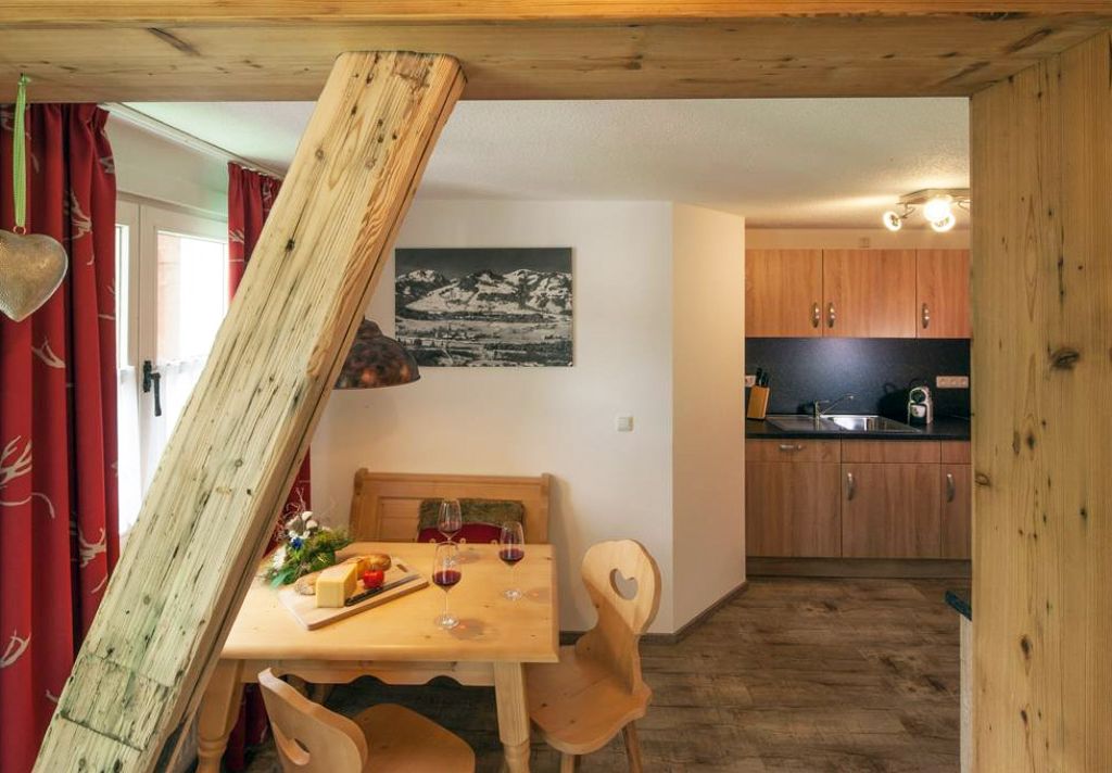Gemütliches Wohnzimmer einer Ferienwohnung im Allgäu mit Holzoptik und voll ausgestatteter Küche – ideal für erholsame Urlaubstage in Fischen.