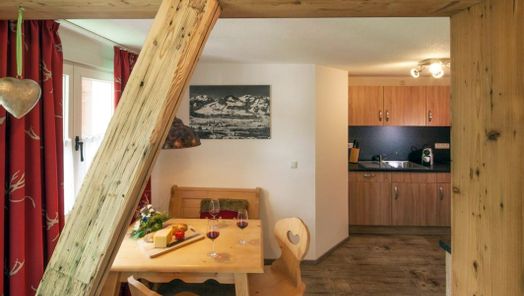 Gemütliches Wohnzimmer einer Ferienwohnung im Allgäu mit Holzoptik und voll ausgestatteter Küche – ideal für erholsame Urlaubstage in Fischen.