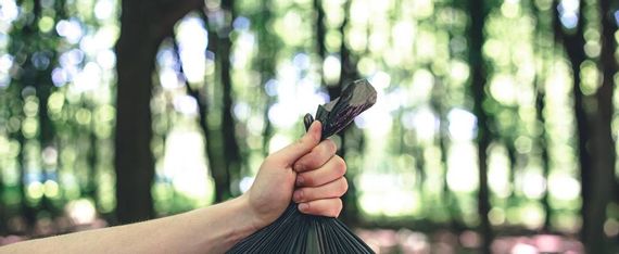 Close-up einer Hand, die eine Mülltüte hält – umweltbewusstes Verhalten beim Wandern und Naturschutz im Allgäu.