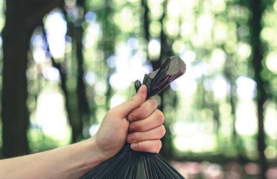 Close-up einer Hand, die eine Mülltüte hält – umweltbewusstes Verhalten beim Wandern und Naturschutz im Allgäu.